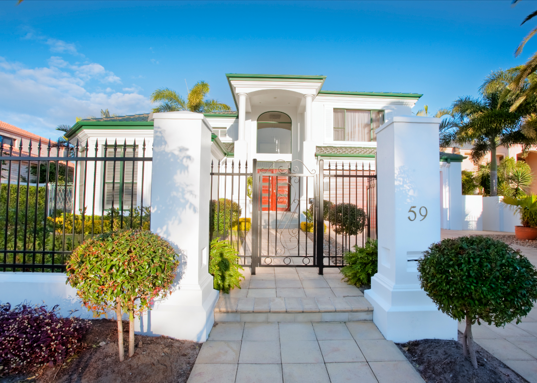 A gated entrance to a modern green and white house.