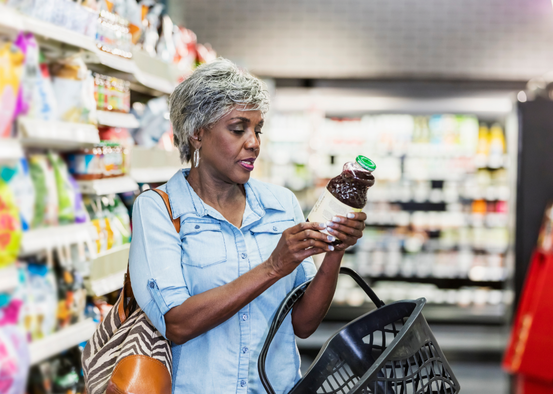 A woman reading a label on a bottled drink.