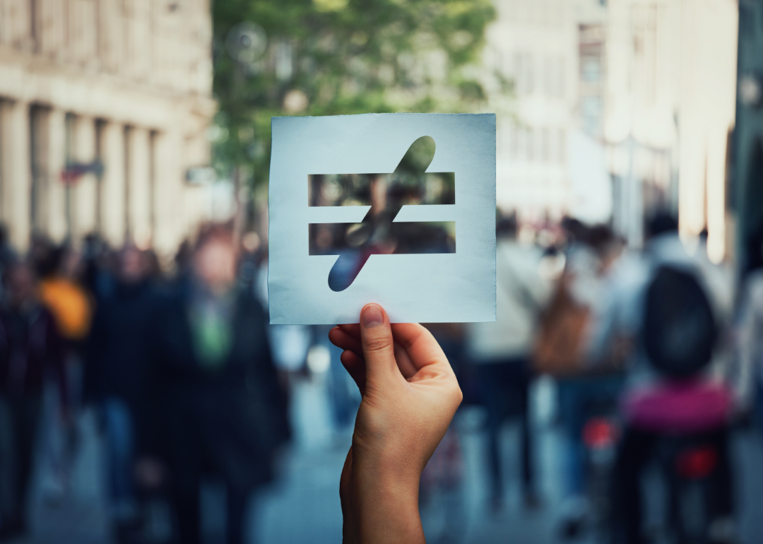 Close-up photo showing a hand holding up a "does not equal" sign