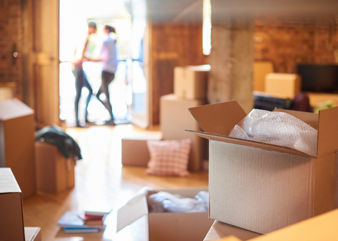 A couple in the background have a discussion while the foreground is filled with moving boxes.
