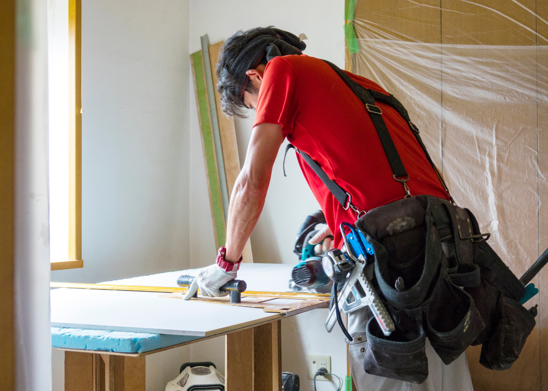 A construction worker cuts wood at a job site.