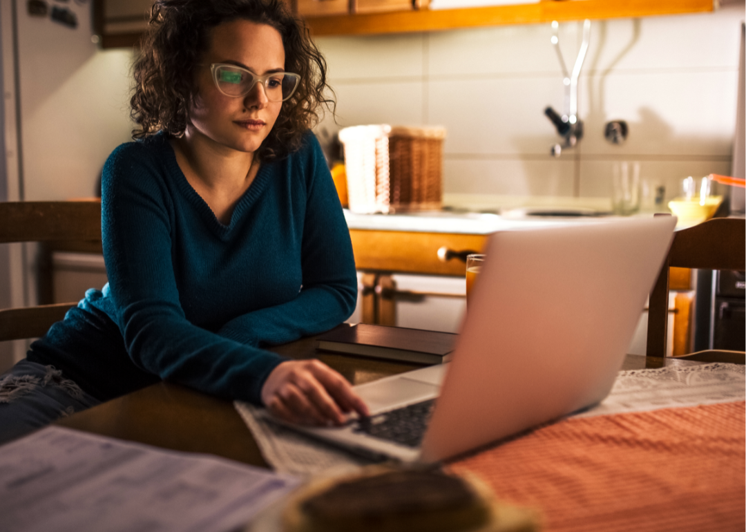 A young woman studies information on a laptop.
