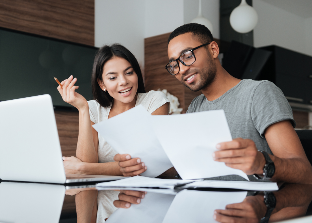 A couple reviewing financial forms together, looking pleased.