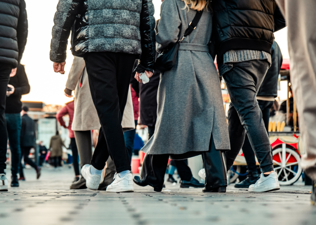 Legs of people walking away from the camera on a city street.