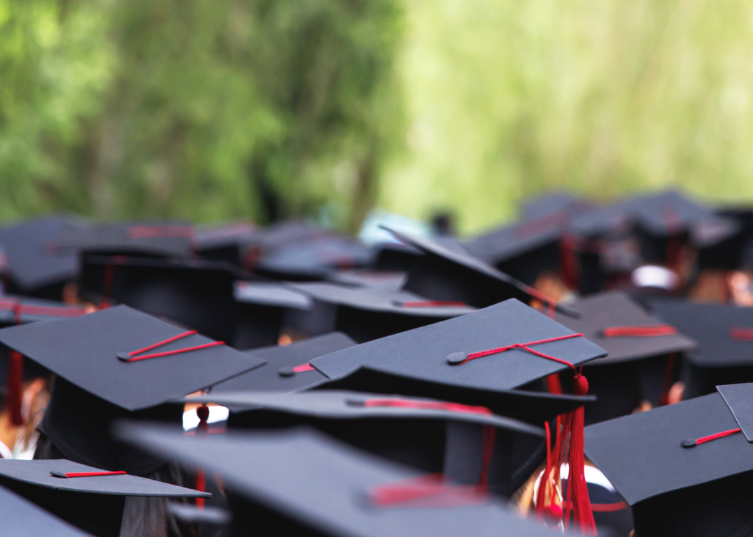 A large group of graduates wearing black mortarboards with red tassles