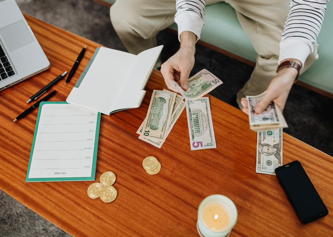 A person divides money into piles at a coffee table.