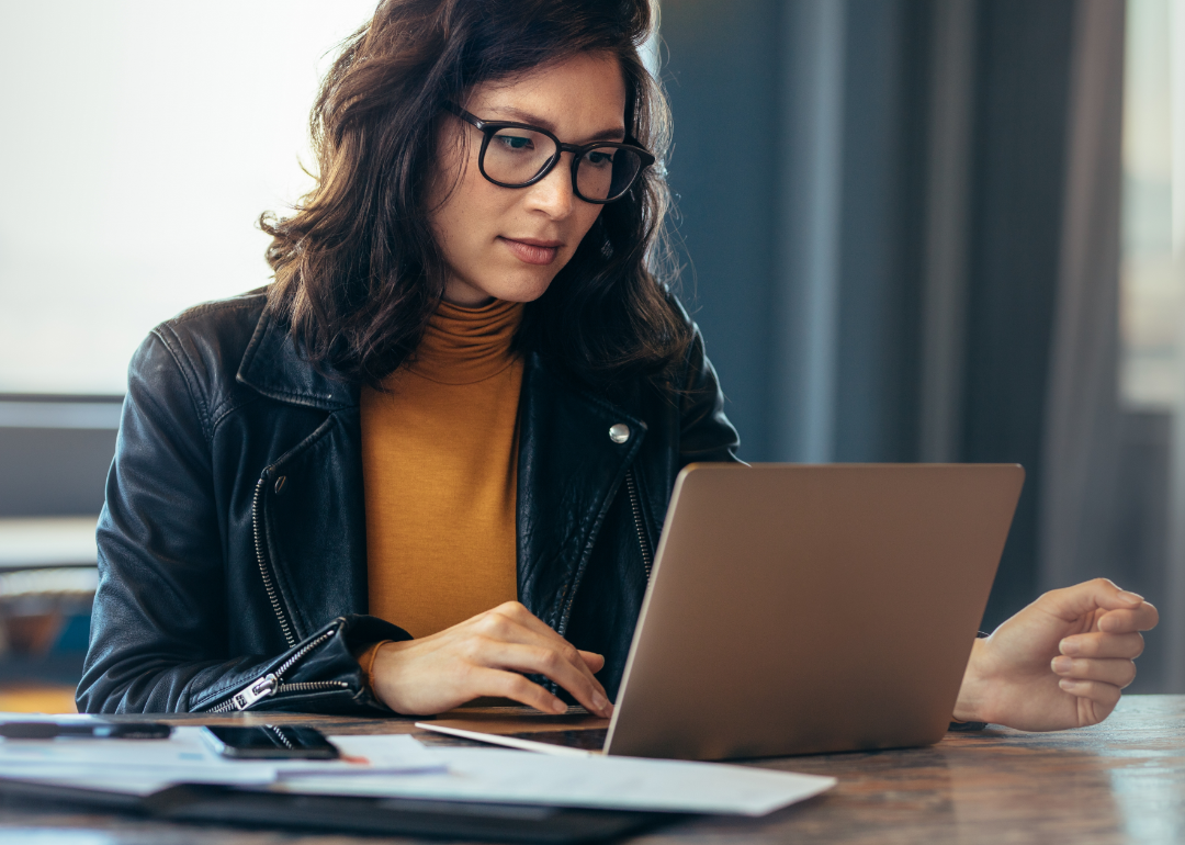 A woman closely studies her laptop.