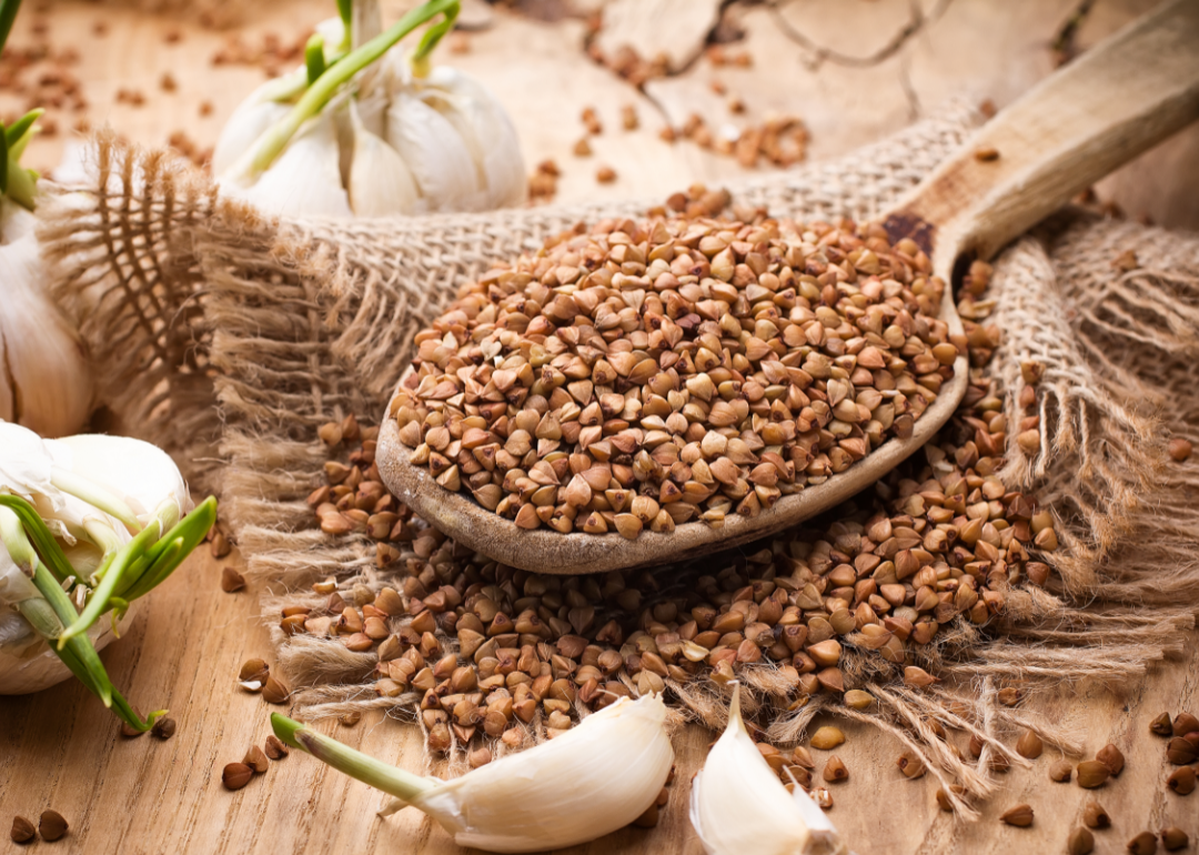 A spoonful of buckwheat on a wood surface.