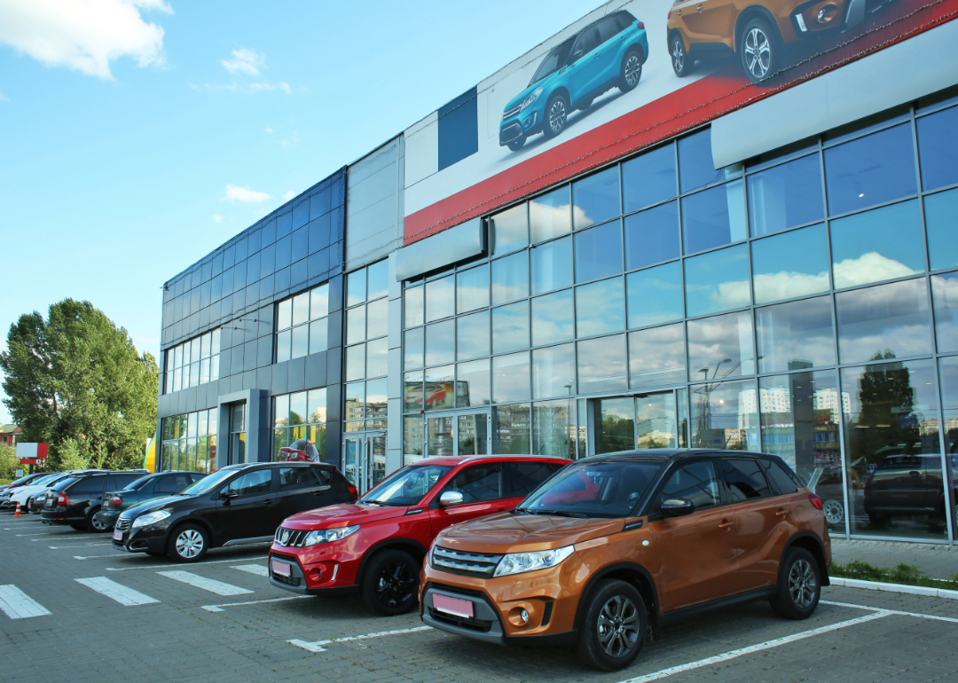 A line of cars in front of an auto dealership.