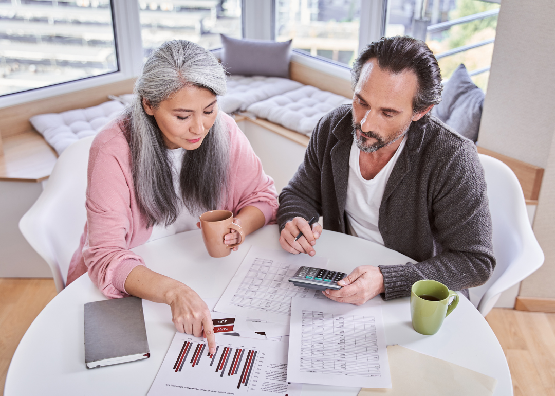 A couple reviews financial documents at a table.