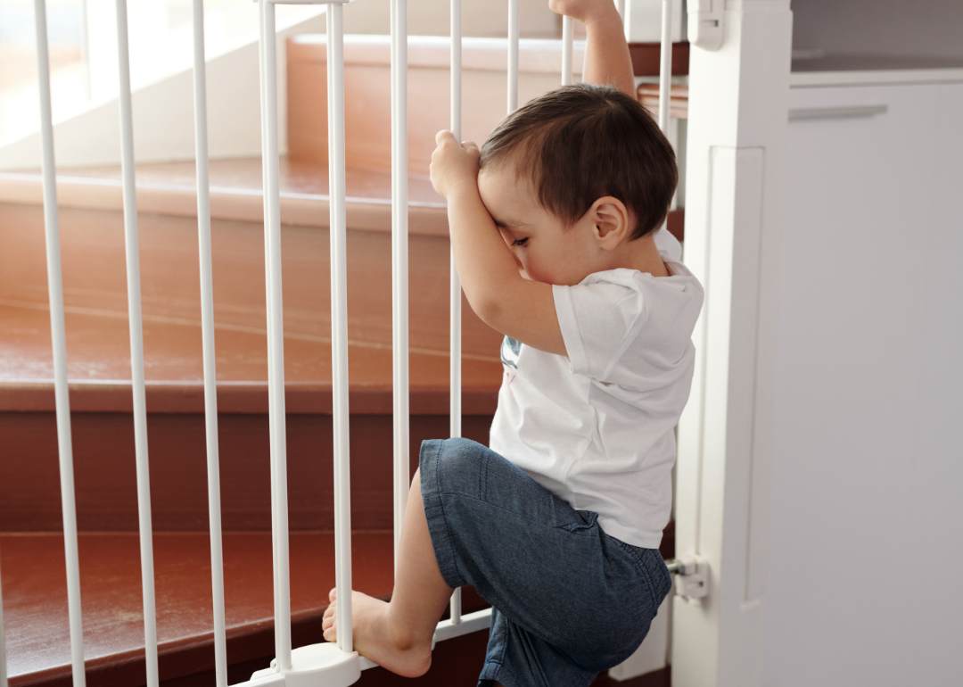 Baby holding onto baby fence rails.
