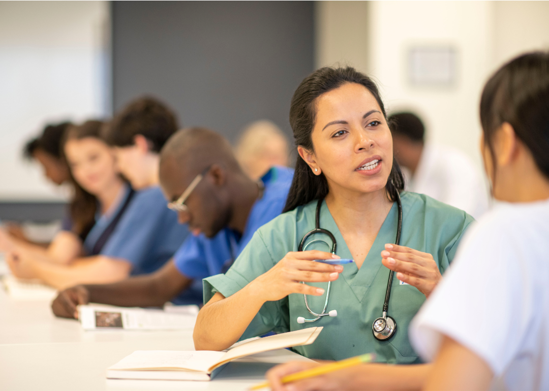 A closeup of a student nurse in a classroom talking to another student.