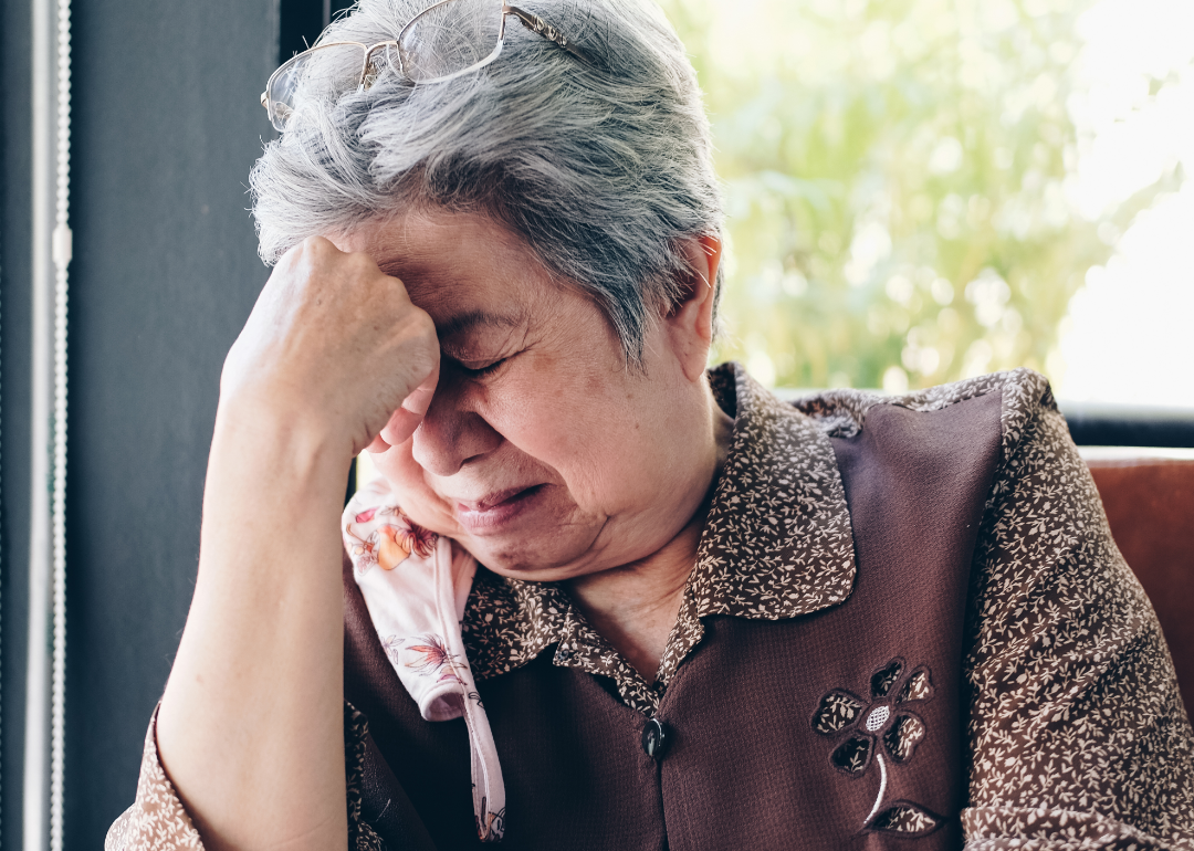 An older woman sits alone crying.