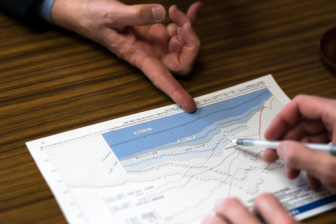 People’s hands point at a chart.