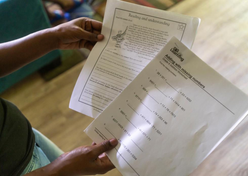 Rosalind Crawford holds two worksheets she printed off for her sons to supplement their education after all five were indefinitely sent home for virtual learning by their school district.