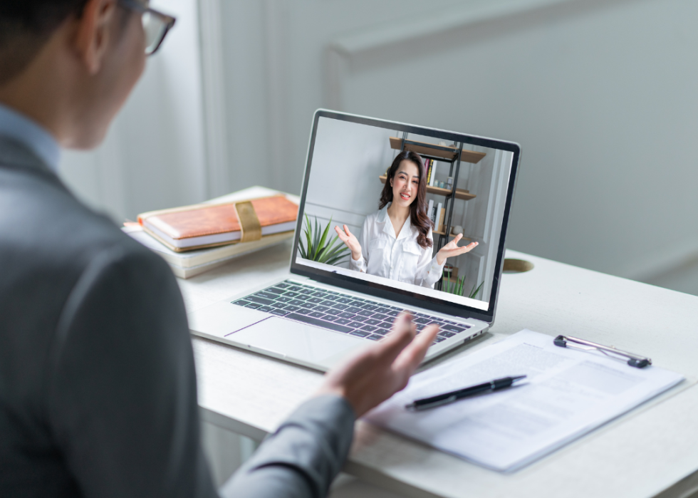 Two coworkers hold a virtual meeting on a laptop computer