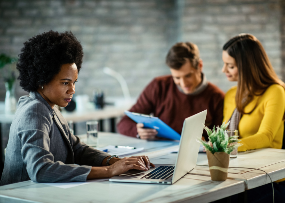 A financial advisor consults her laptop during a meeting with clients.