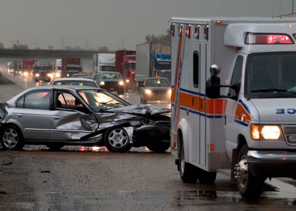 Car smashed on the side of the highway during rainy day.