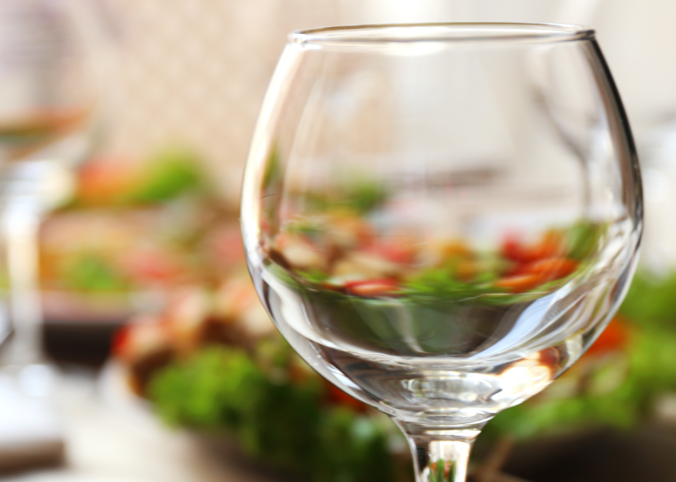 Colorful vegetables seen through an empty wine glass.