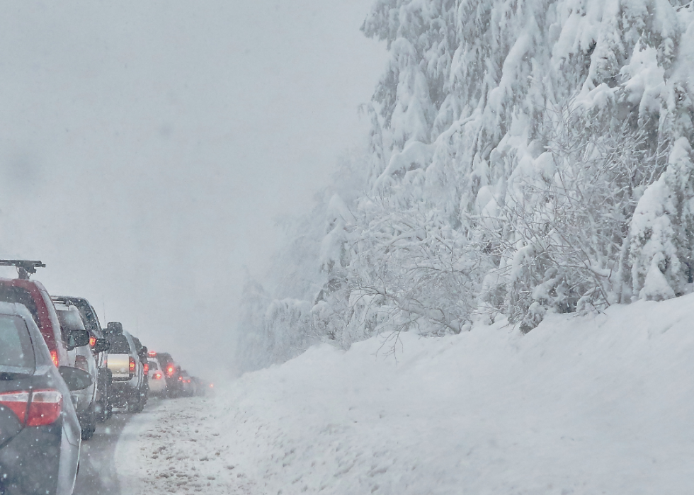 Cars driving along snowy road.