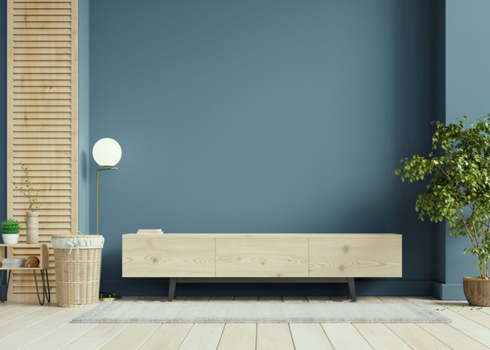 A low white bureau stands against a deep muted blue wall in a modern room