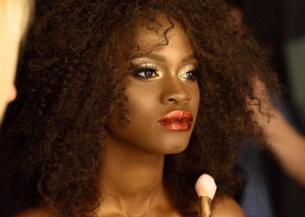 Woman wearing dramatic gold eye makeup and metallic lipstick.