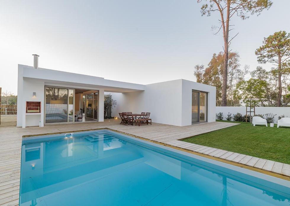Backyard pool is seen in a modern yard with turf.