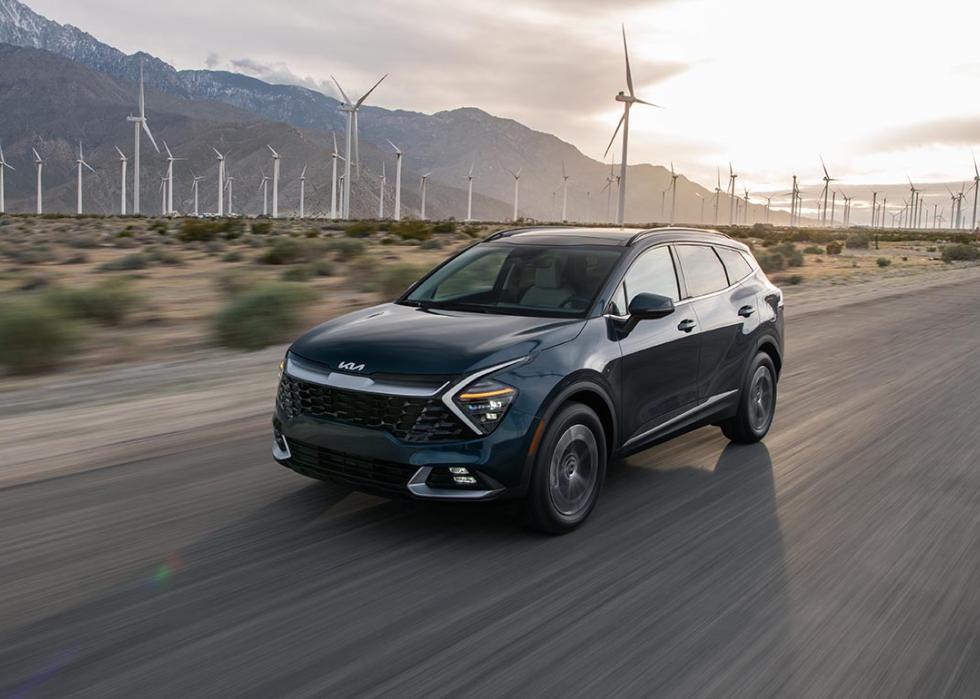 Photo of Black Kia Sportage Hybrid driving with windmills in the background in the desert.