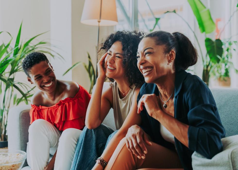 A group of three women hanging out and sitting on a couch together.