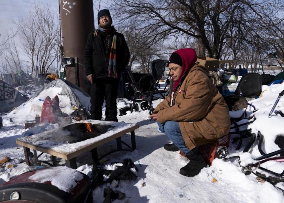 Two unhoused individuals sit around a fire in the homeless camp in Oklahoma City, Oklahoma.