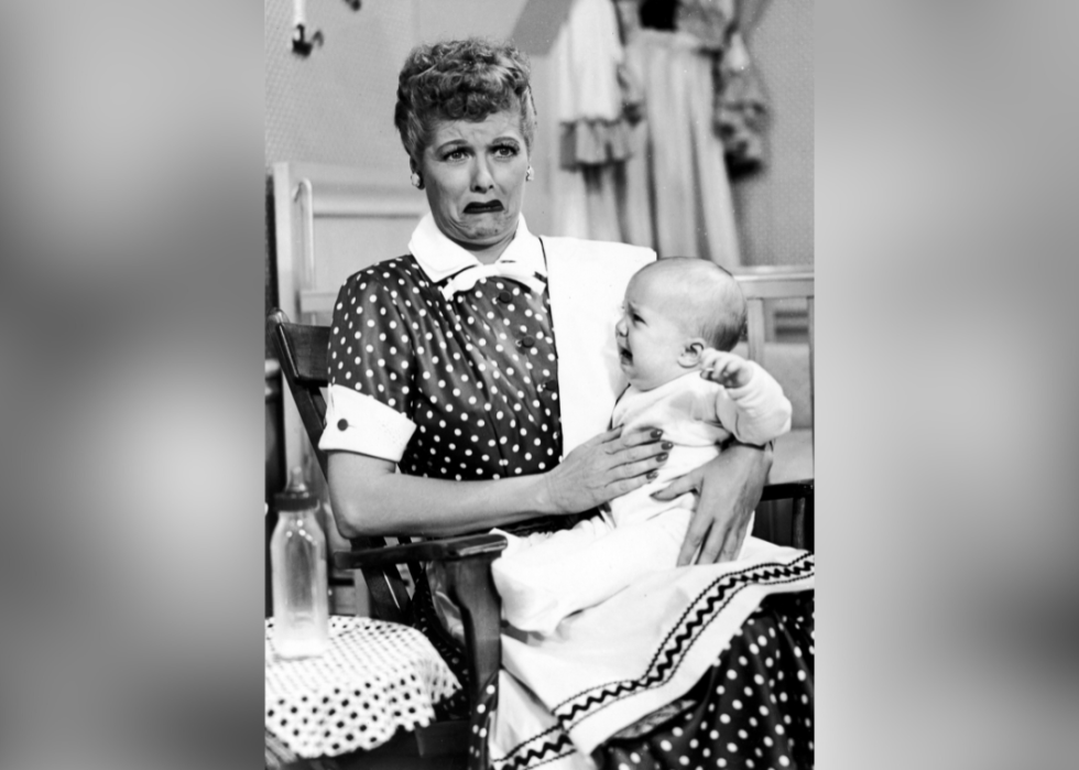Lucille Ball with an overwhelmed, crying face holds a crying infant in the 1953 I Love Lucy episode No Children Allowed.