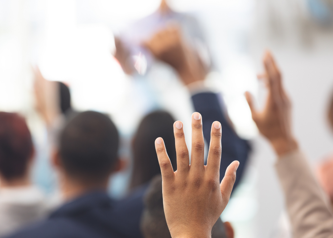 Selective focus of hand raised in classroom.