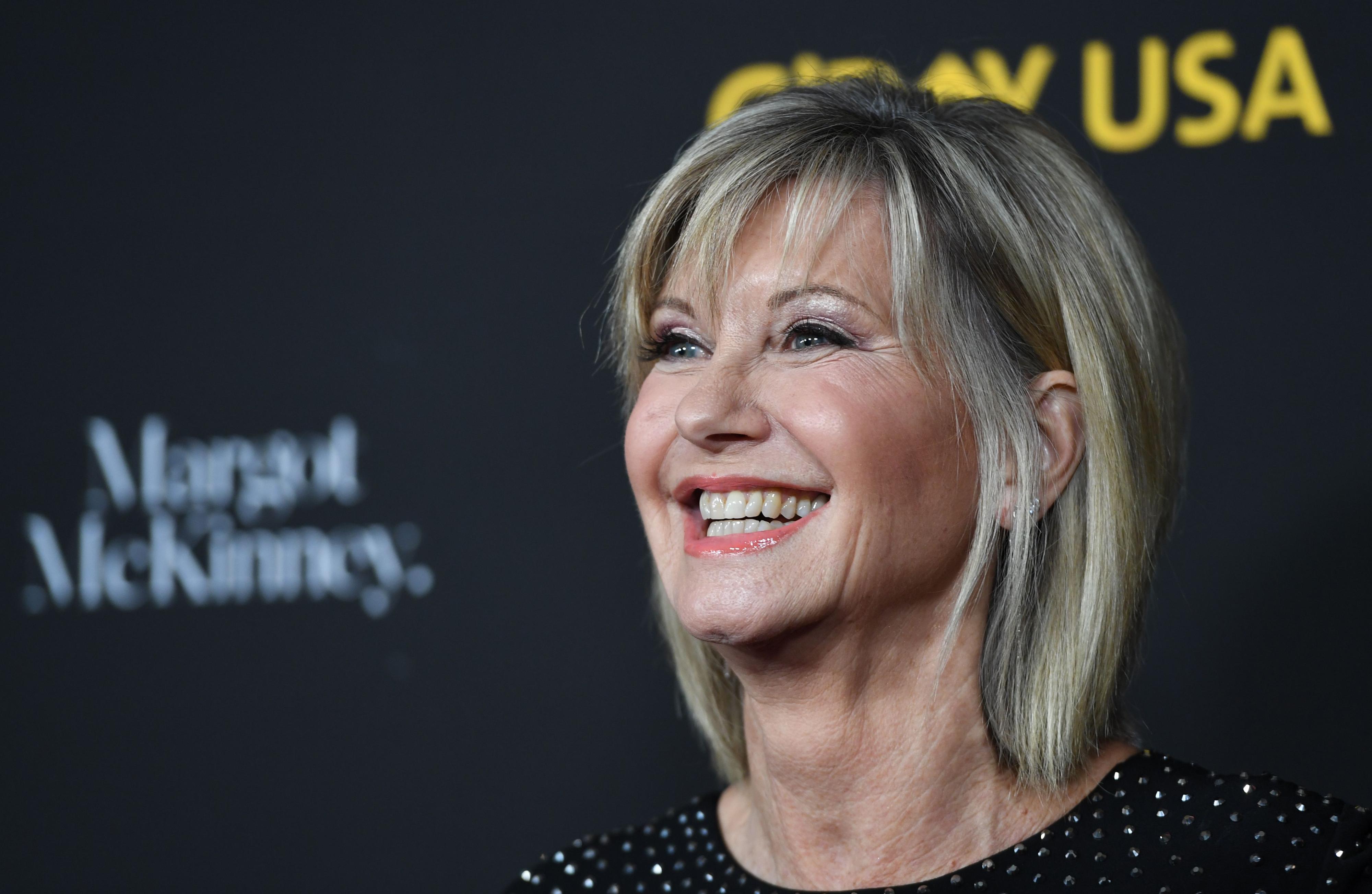 Olivia Newton-John smiles for photographers.