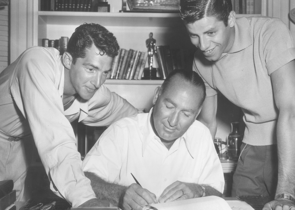 Hal B Wallis sits at his desk with Dean Martin and Jerry Lewis.