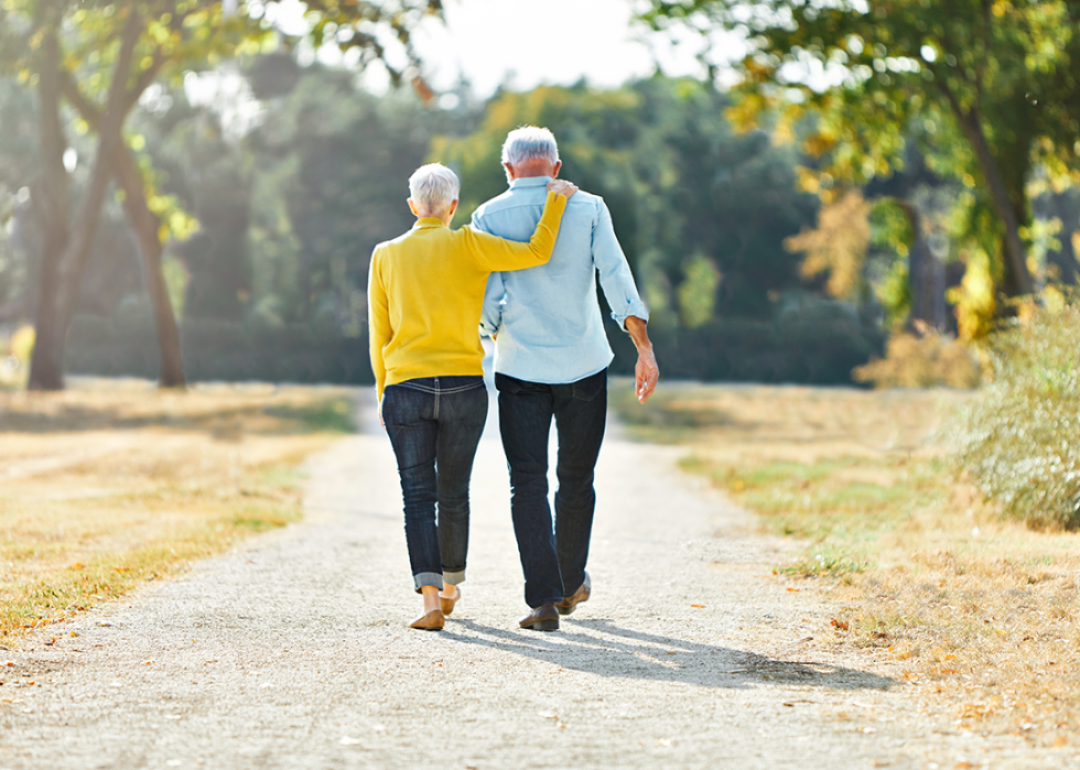 Senior couple walking and holding hands outdoors.