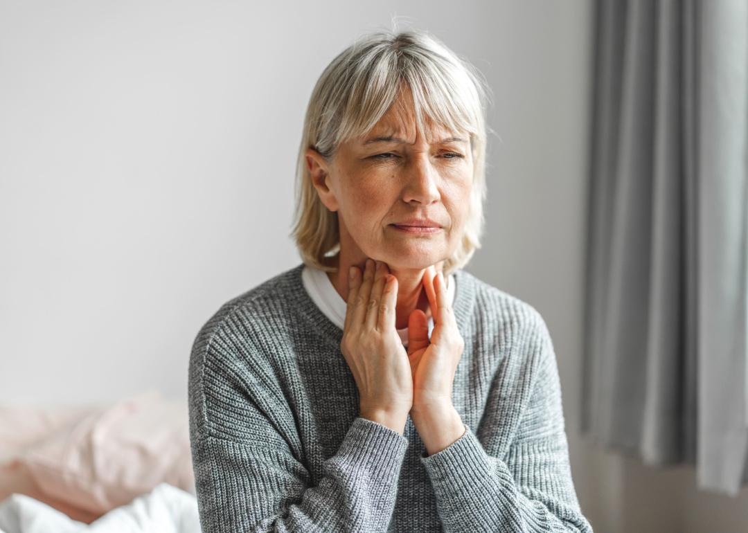 Woman touching neck and throat.
