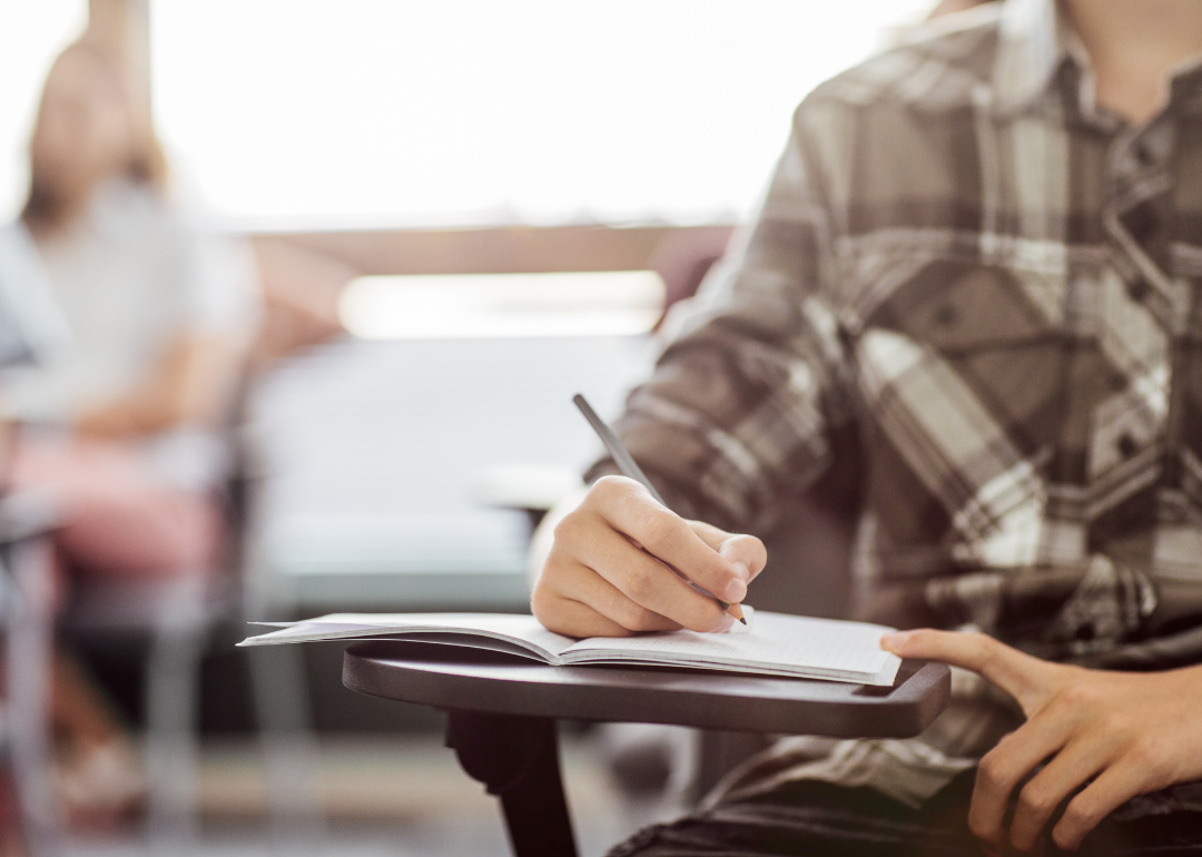 Closeup of male student writing in notebook