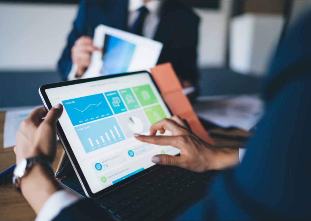 Person reviewing reports on tablet in business meeting.