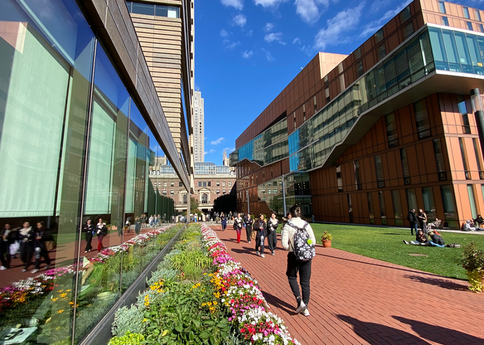 Students walking on a red brick path past the Milstein Center (left) and Diana Center (right) on the Barnard College campus.