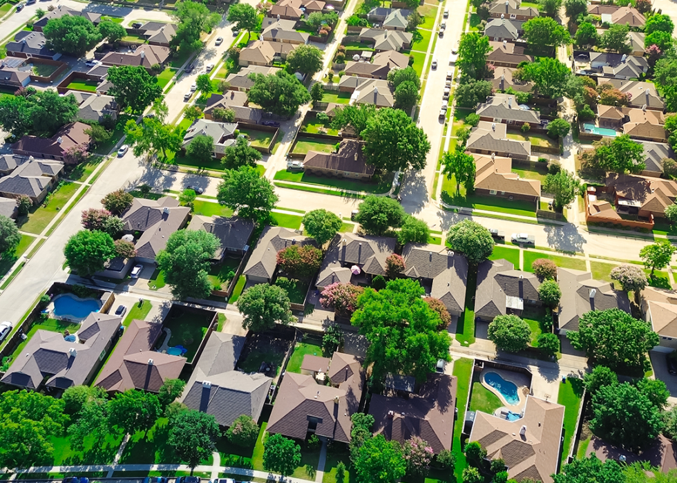 Aerial view of suburban houses with swimming pool in upscale residential neighborhood.