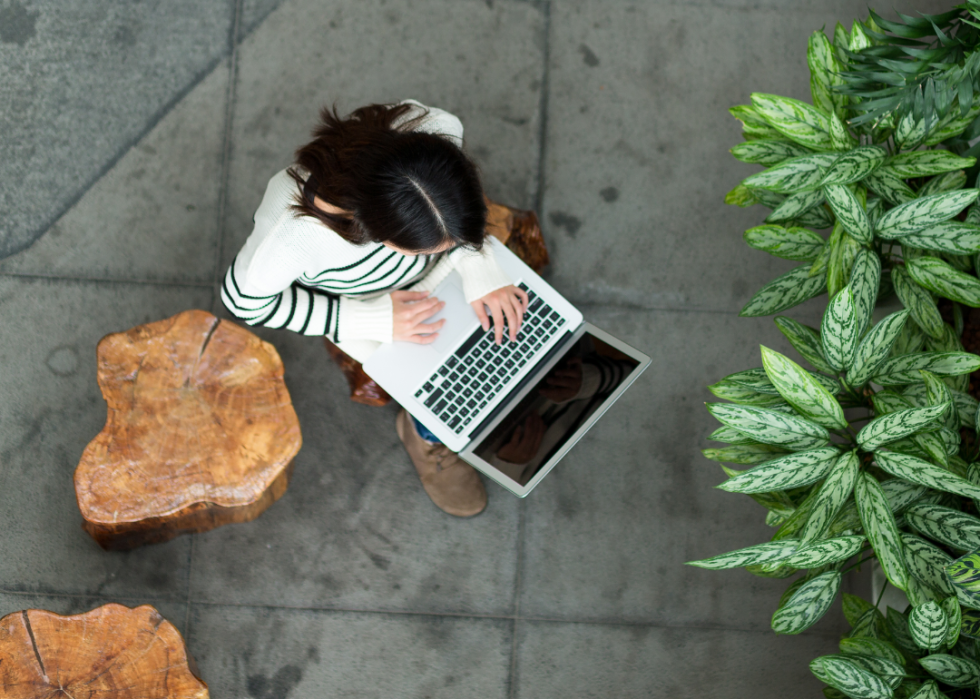 A student works on a laptop in an open courtyard.