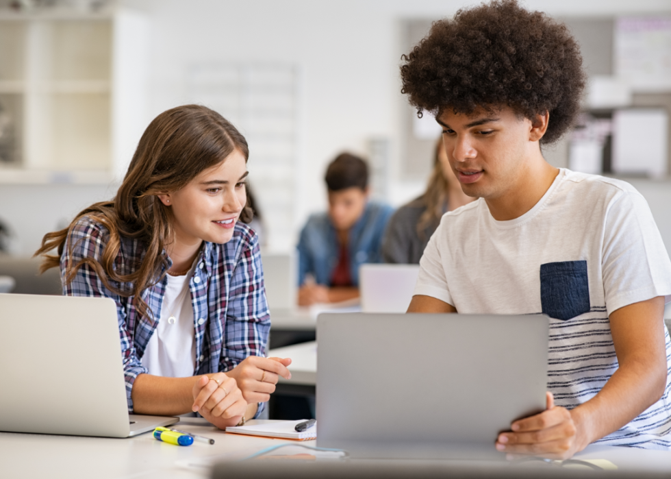 Two students share a laptop.