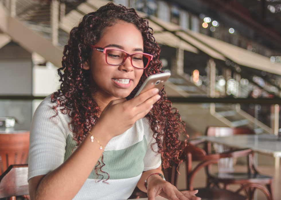 A woman speaking into the cell phone she is holding close to her mouth.