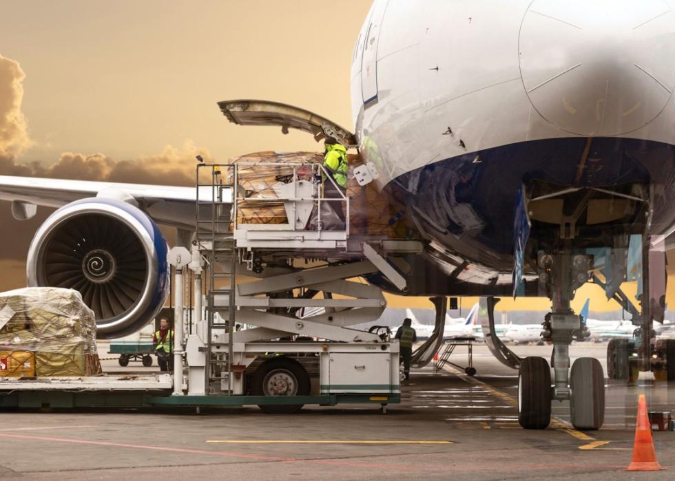 Few people in green vests are loading cargo on to the plane at the airport.