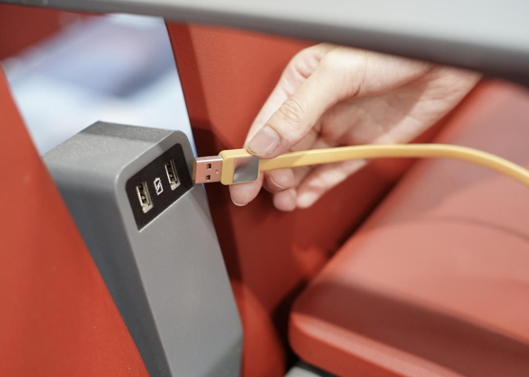 A person plugging in a phone charger between seats.