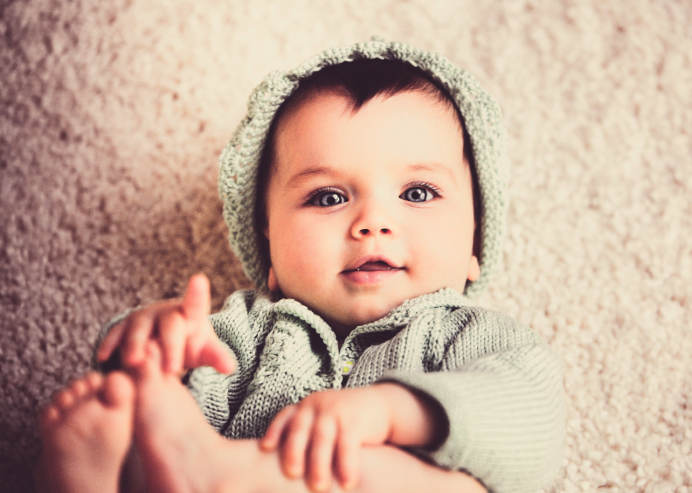 A baby boy with blue eyes in green outfit.