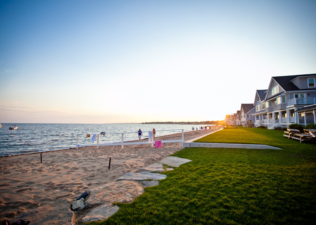 People walking on a beach lined with large homes.