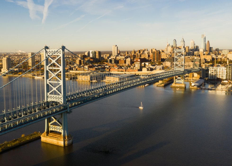 A tall suspended bridge over the river with city views. 