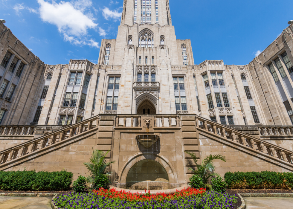 A historic Gothic university building with a fountain.