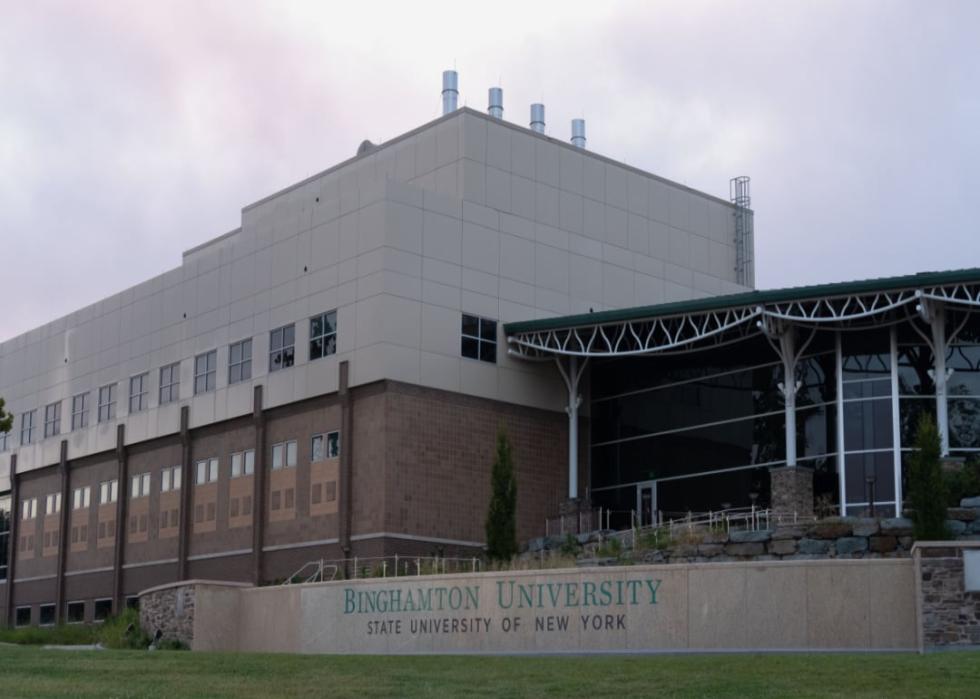 A modern white and brown building with a sign that says Binghamton University. 